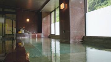 A wet indoor area with a staircase, large windows, and a view of greenery outside.