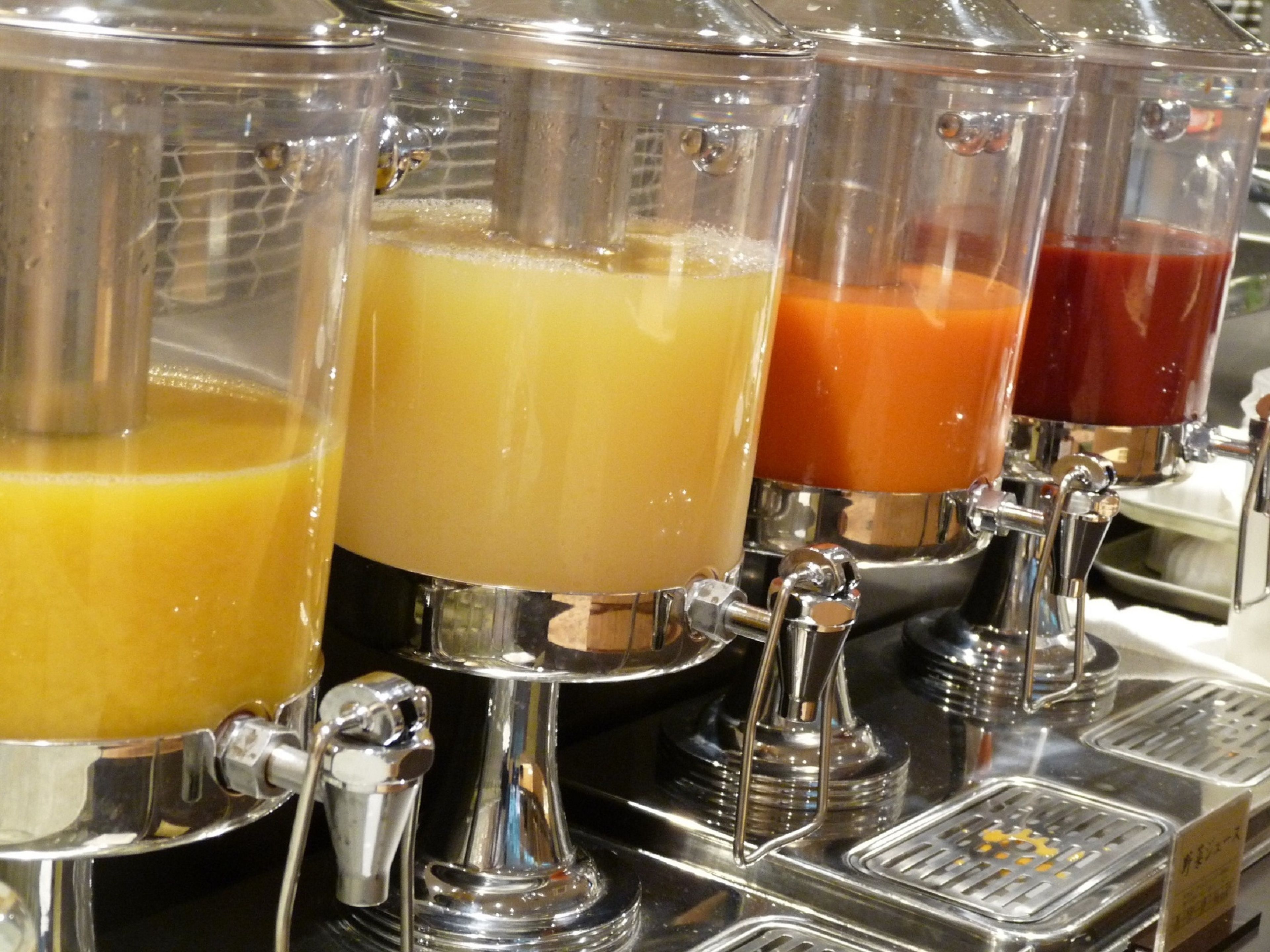 A juice dispenser with four different colored drinks.