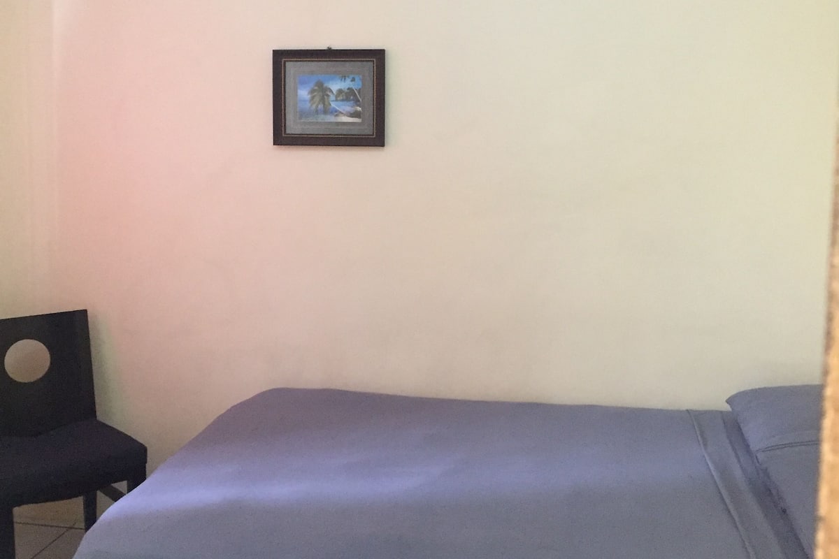 Une pièce comprenant un lit, une chaise et un tableau encadré accroché au mur.