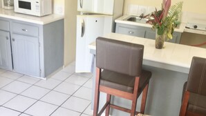 Un espace de vie compact comprenant un coin cuisine, un coin repas et un coin salon avec une petite table et un canapé.