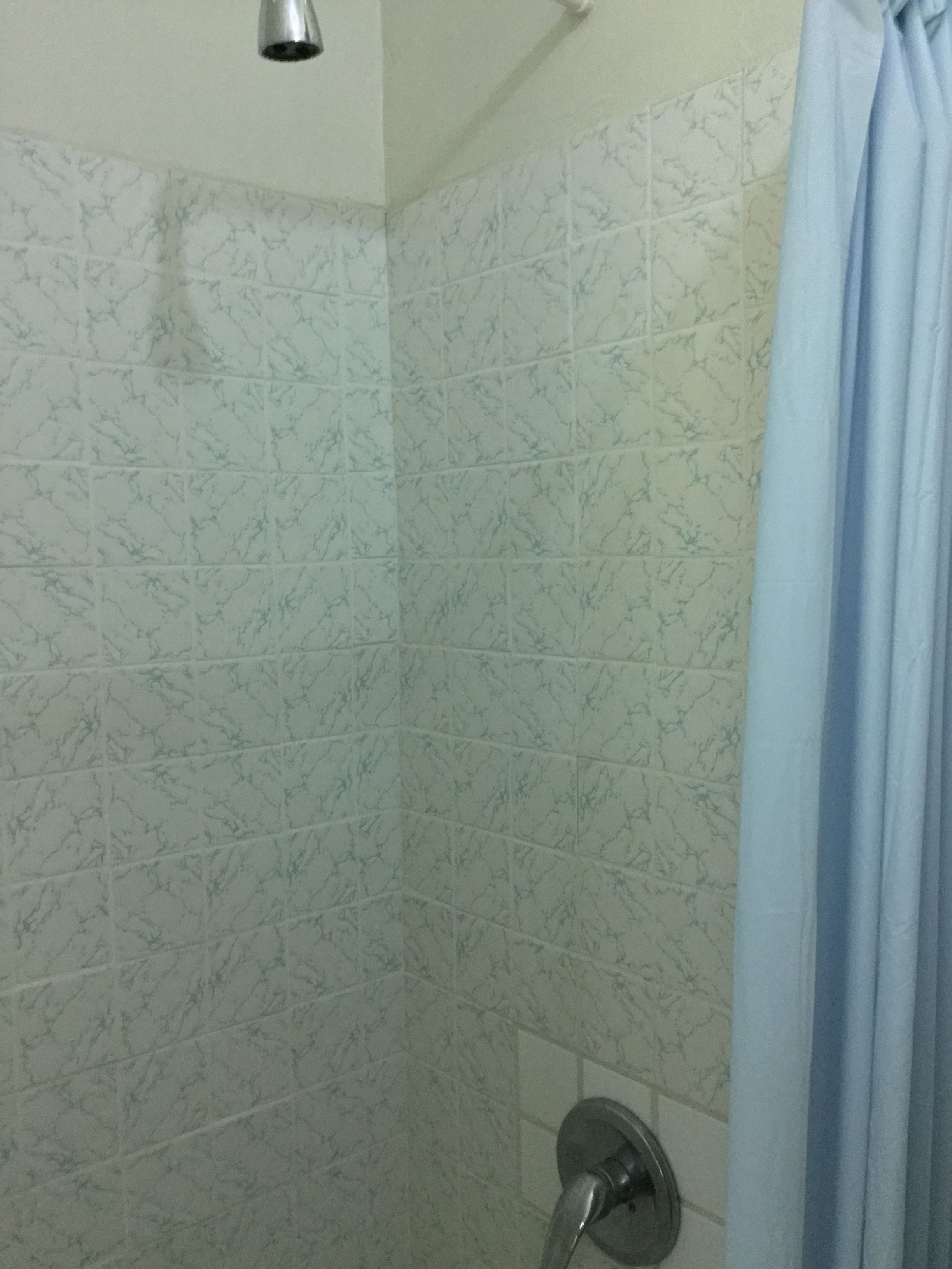 Un baño con azulejos de mármol blanco y una cortina de ducha.