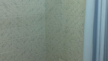 Un baño con azulejos de mármol blanco y una cortina de ducha.