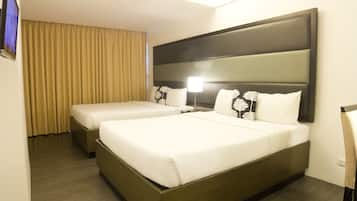 A hotel room with two beds, a flat-screen TV, and a large window with curtains.