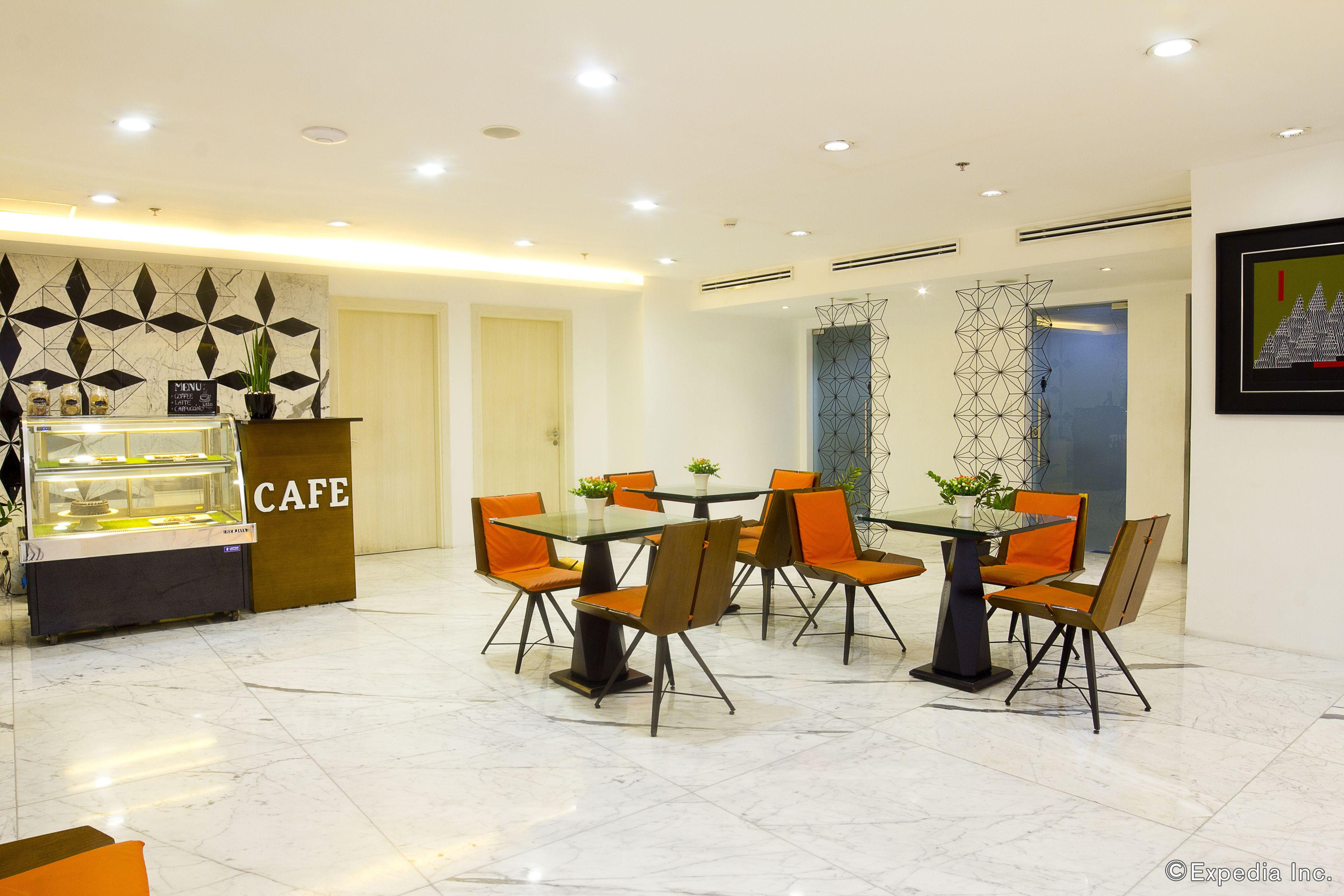 A cafe with a glass-top table and orange chairs, a menu sign, and a decorative wall.