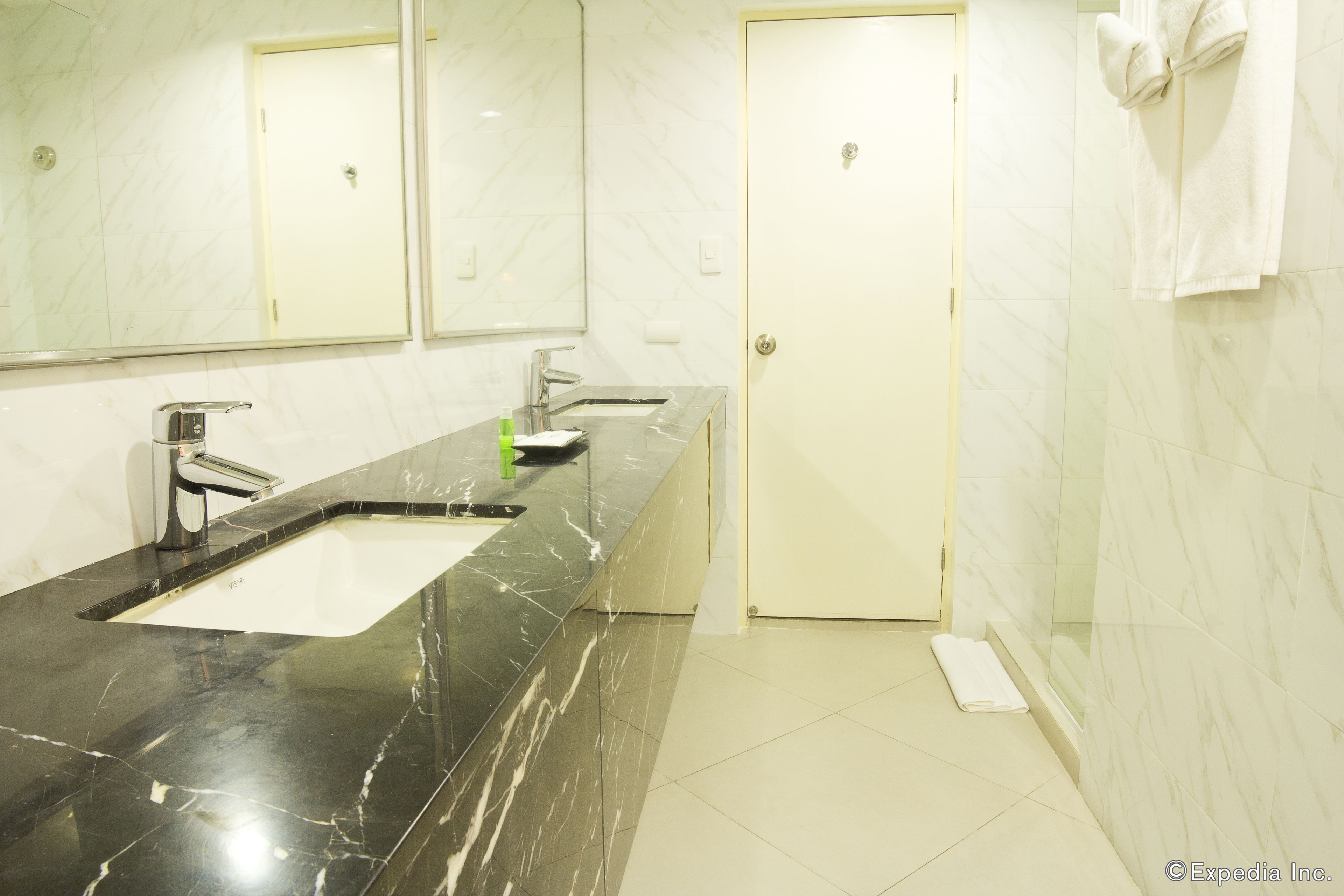 A modern bathroom with a black marble sink, a mirror, and a white door.