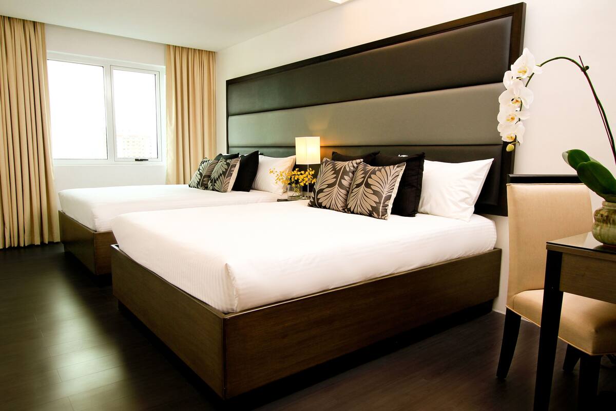 A double bed with a dark headboard, two bedside tables with lamps, and a potted orchid.
