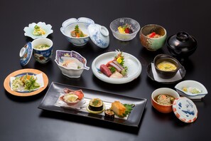 Diverse Japanse gerechten en kommen op een zwarte tafel.