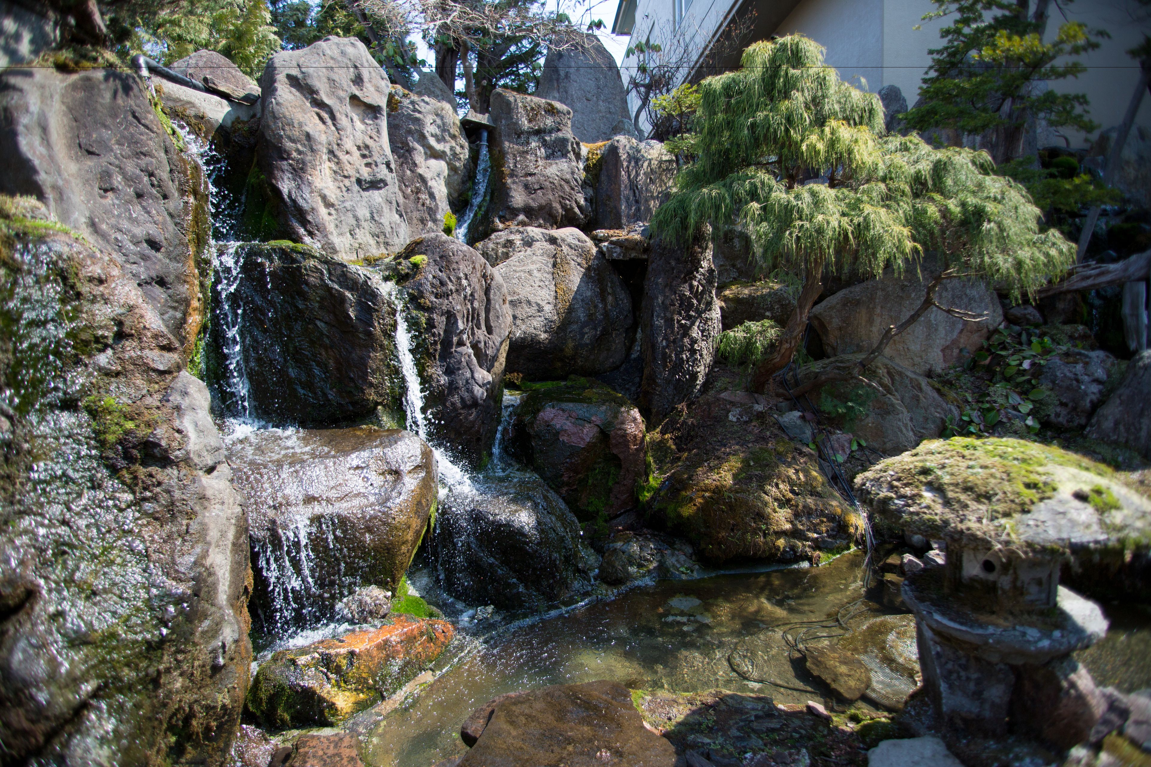 A natural rock formation with a small waterfall and a pond.