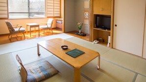 A traditional Japanese room with tatami flooring, a low wooden table, and a television. - Ryokan Sensyoen (Asahikawa)