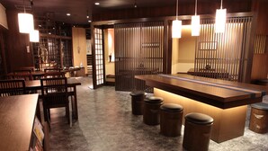 A restaurant interior with wooden furniture, a central counter, and hanging lights. - Ryokan Sensyoen (Asahikawa)