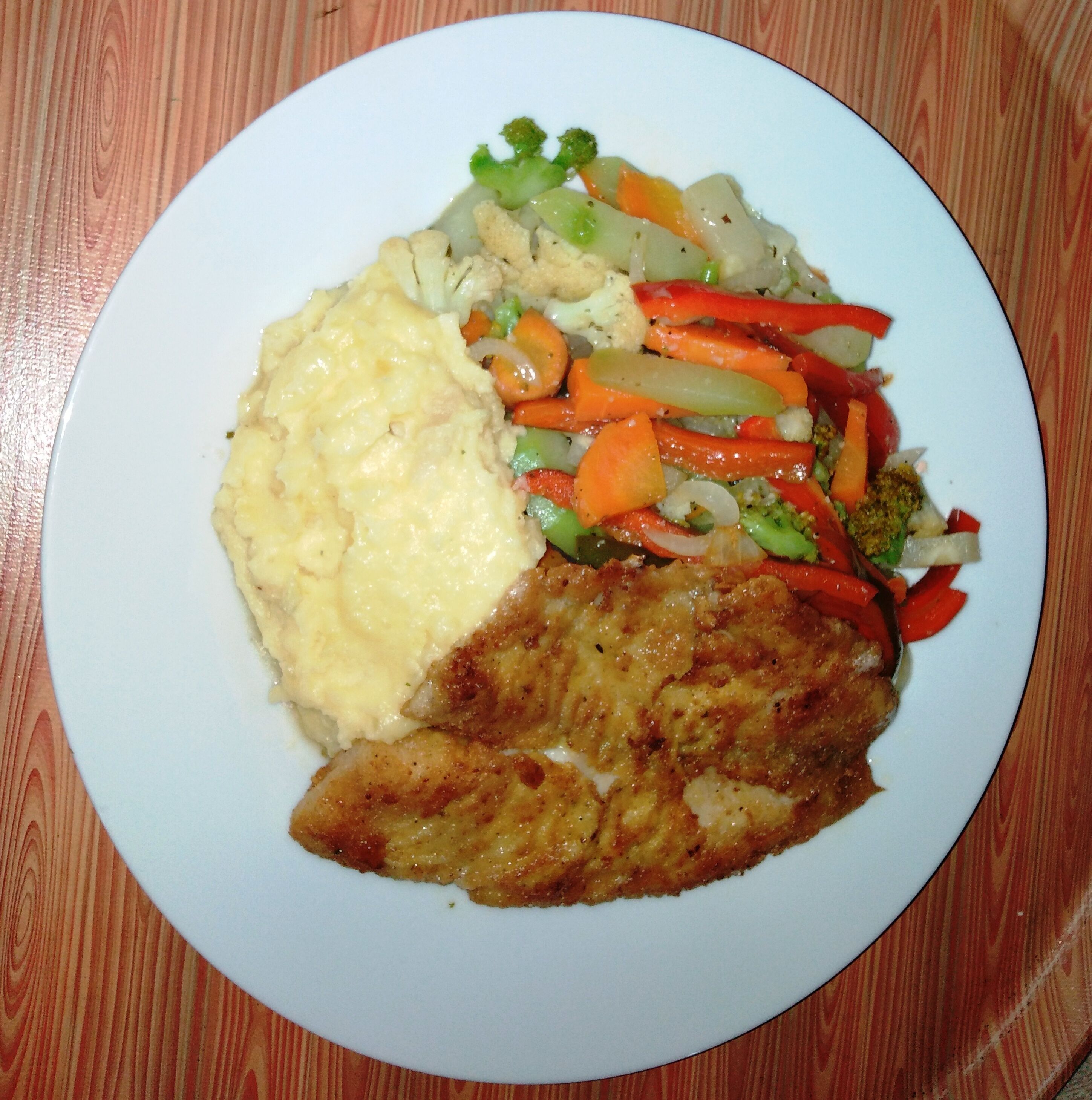 A plate with mashed potatoes, a piece of meat, and a vegetable medley.