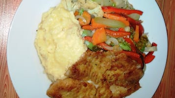 A plate with mashed potatoes, a piece of meat, and a vegetable medley.