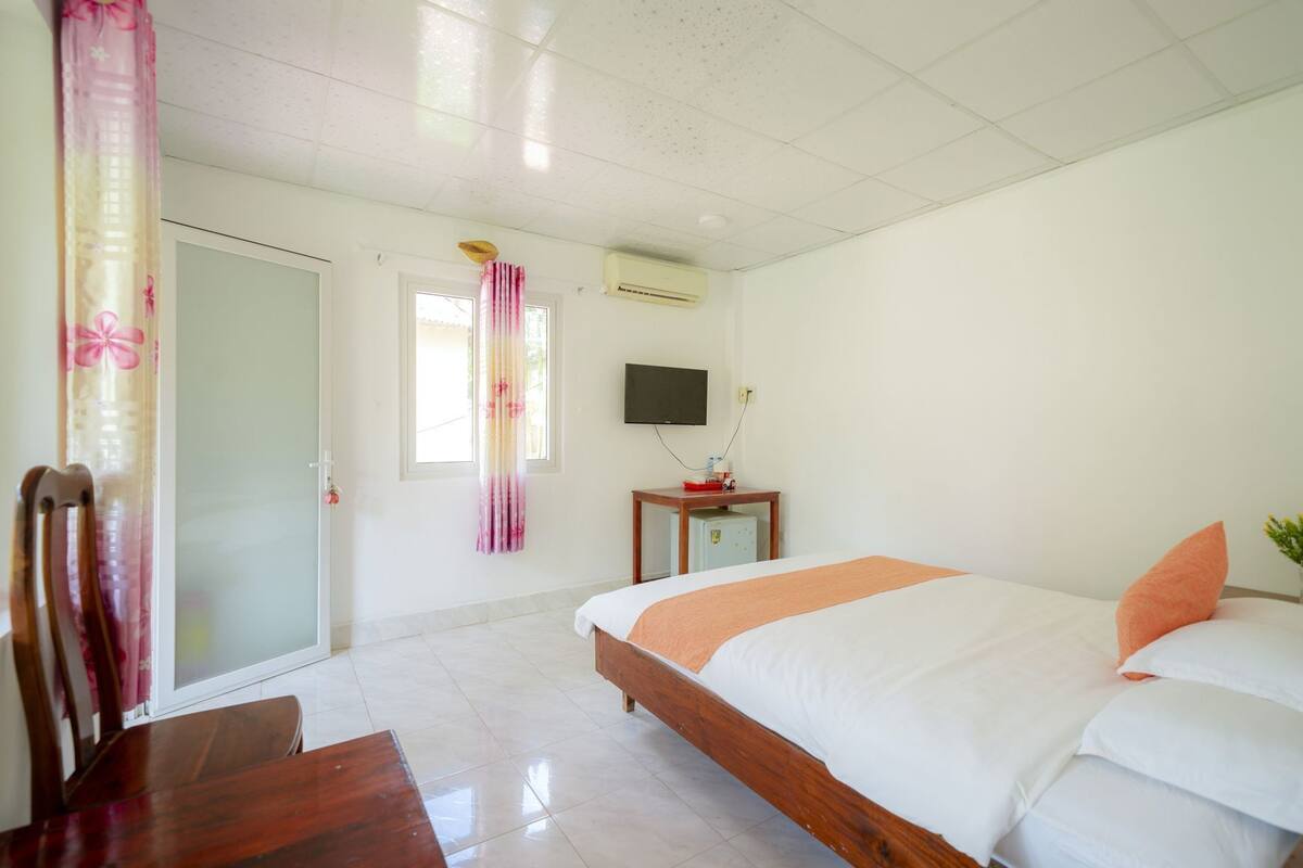 Ein Hotelzimmer mit Bett, Schreibtisch, Stuhl, Fernseher und kleinem Kühlschrank.