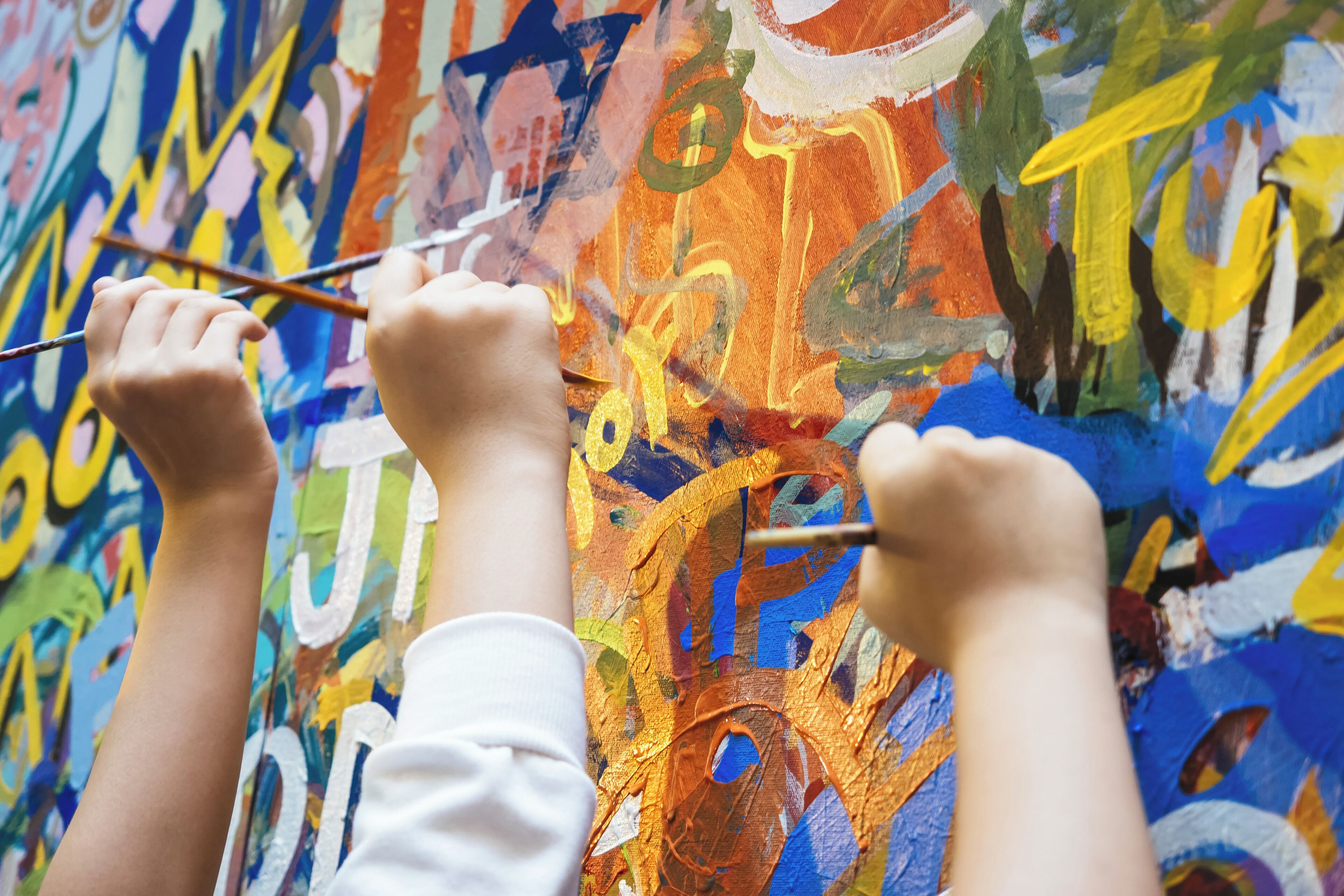 A person painting on a colorful abstract mural.