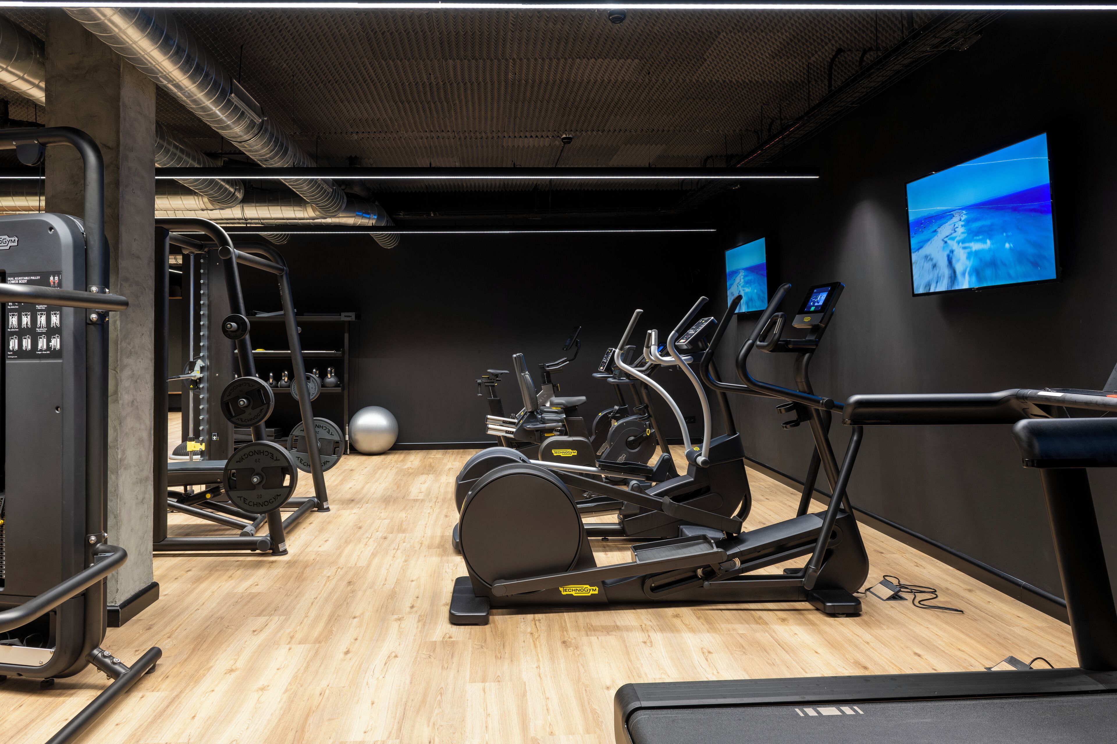 A gym with cardio machines, weightlifting equipment, and a large exercise ball.