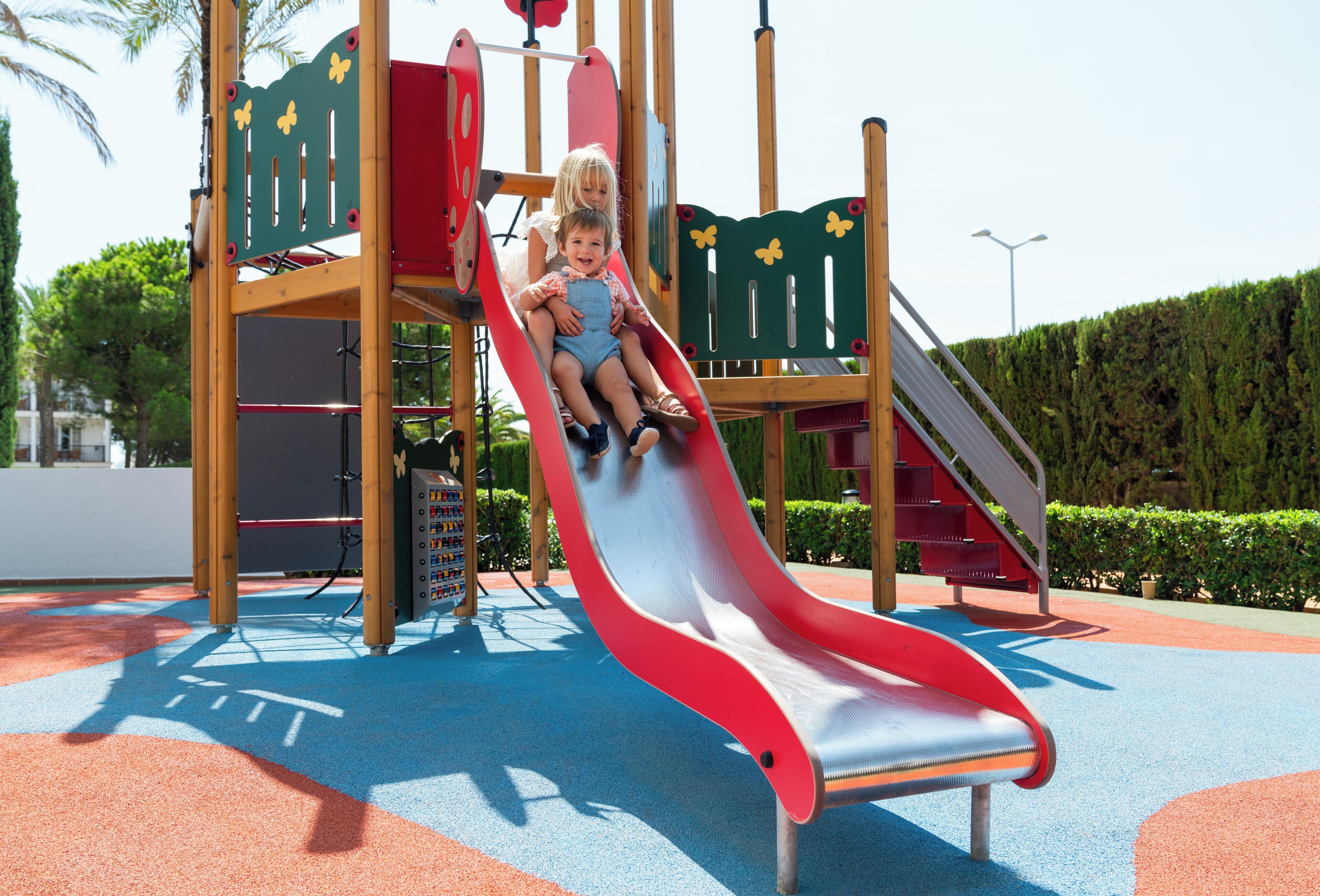 A playground with a red slide and a climbing structure.