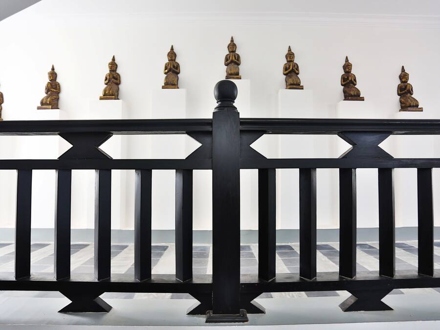 Une balustrade noire, dotée de barreaux verticaux régulièrement espacés et d’un pilastre central.
