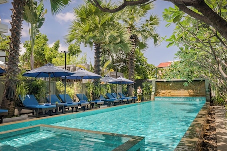 Una piscina al aire libre, sillones reclinables de piscina