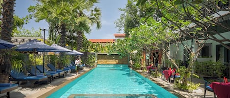 Een buitenzwembad, ligstoelen bij het zwembad