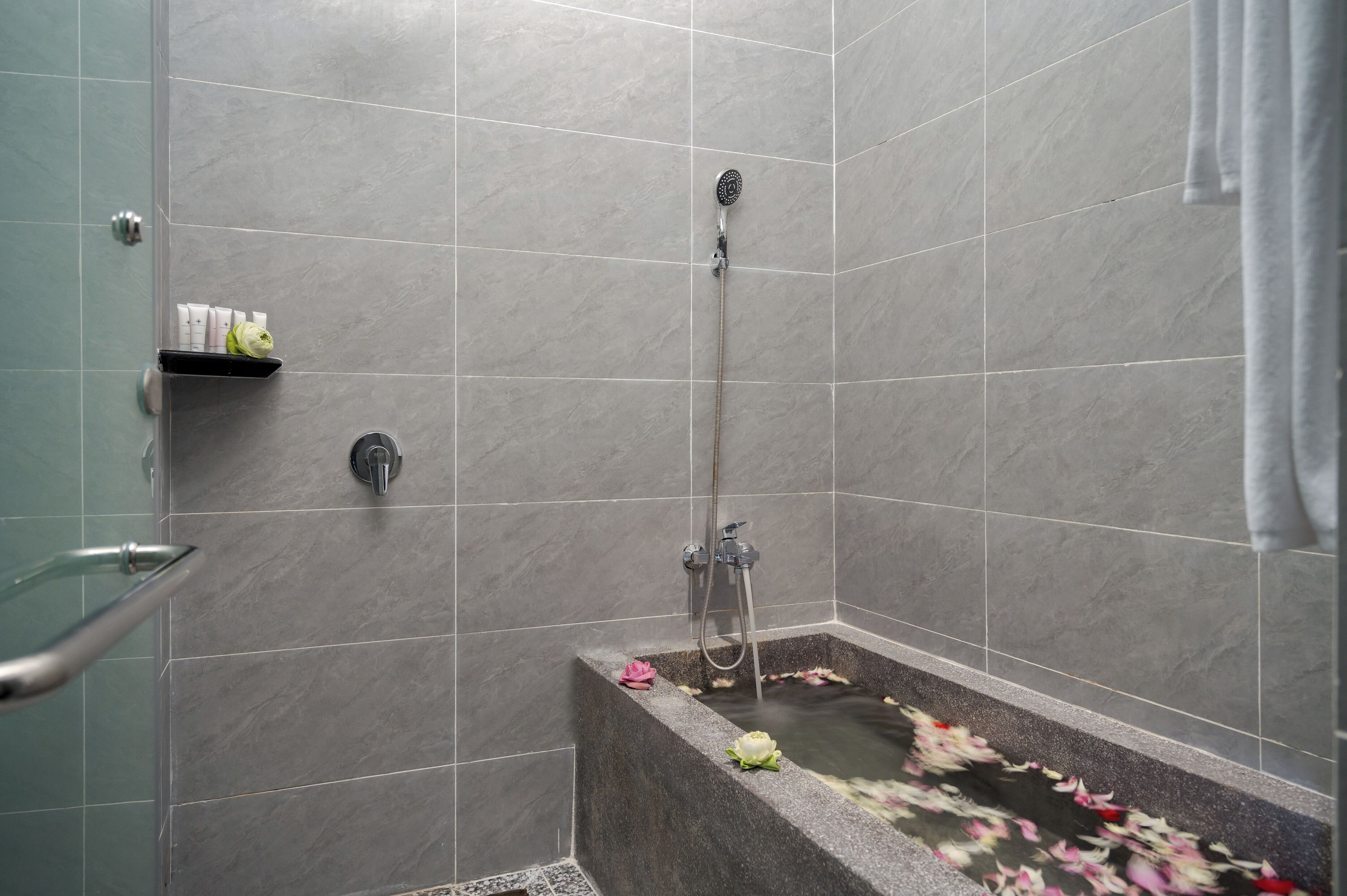 A modern shower area with a handheld showerhead, a built-in seat, and a shelf with toiletries.
