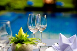 Two empty wine glasses on a table with a potted plant and a folded napkin.