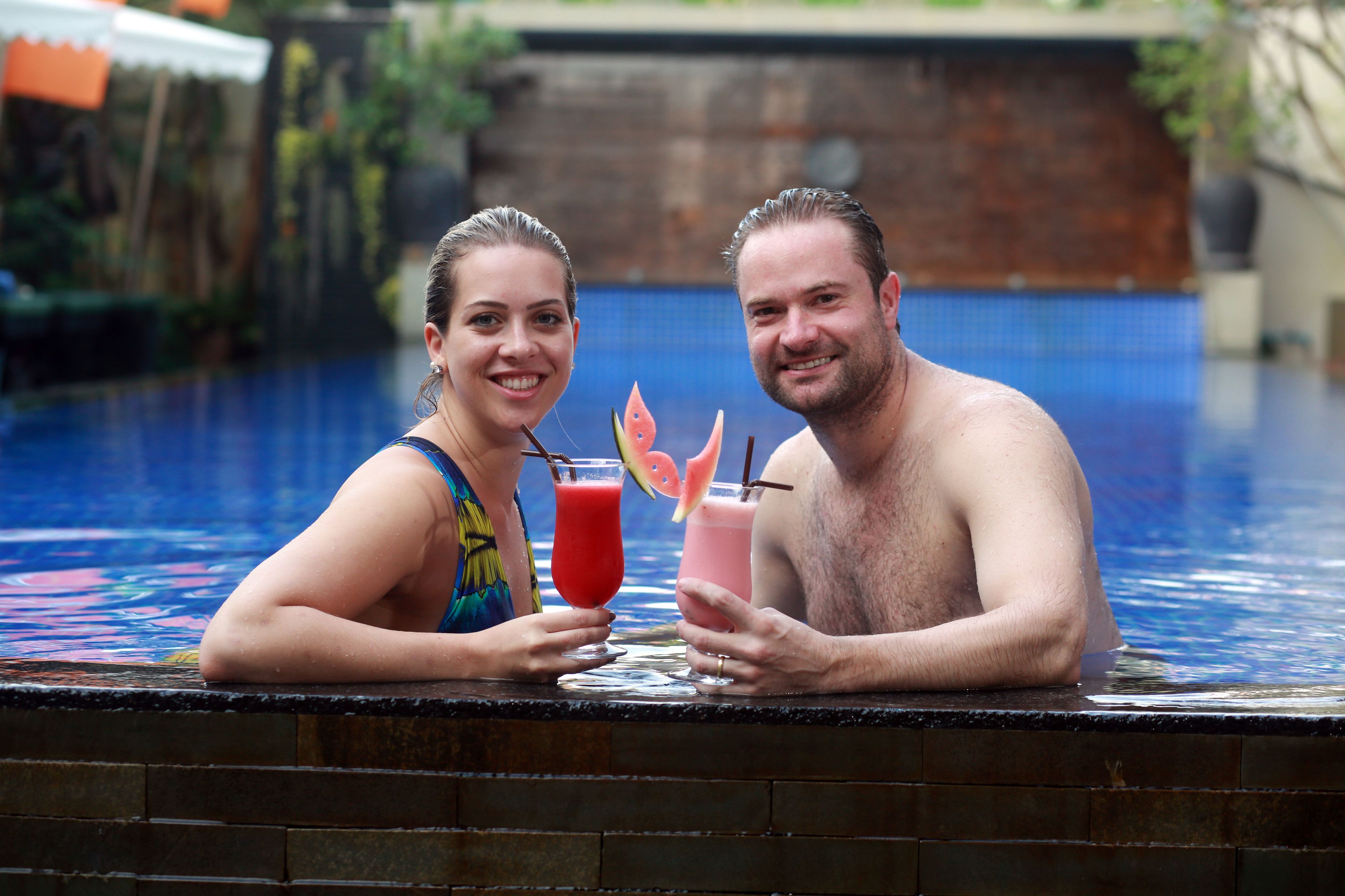 Two people sitting by a pool with drinks.