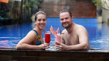 Two people sitting by a pool with drinks.
