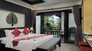 A hotel room with a bed, a bench, a desk, and a balcony with a view of greenery. - Khmer Mansion Boutique Hotel (Siem Reap)