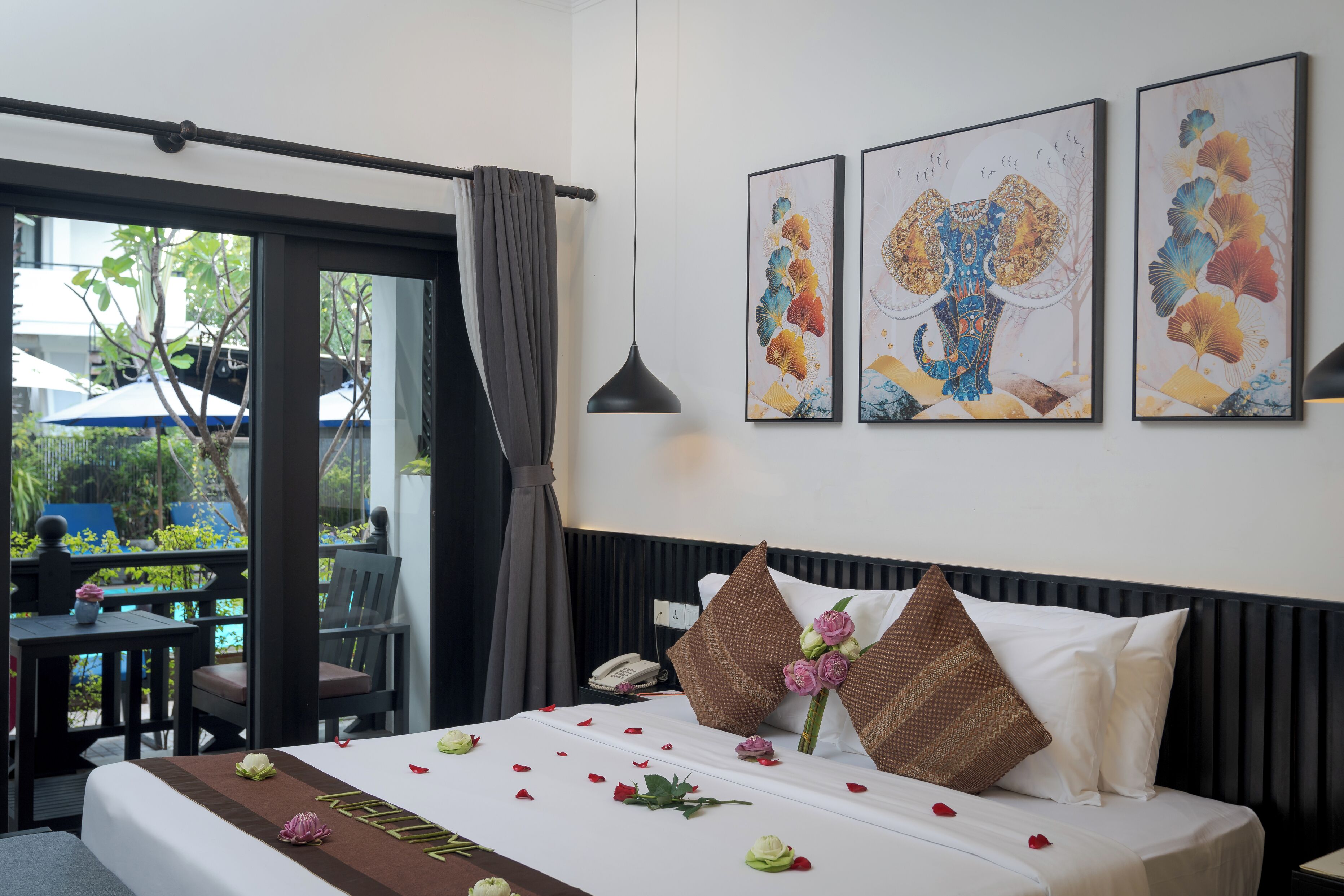 Een hotelkamer met een bed, een bureau en een stoel. Drie kunstwerken hangen in lijsten aan de muur.