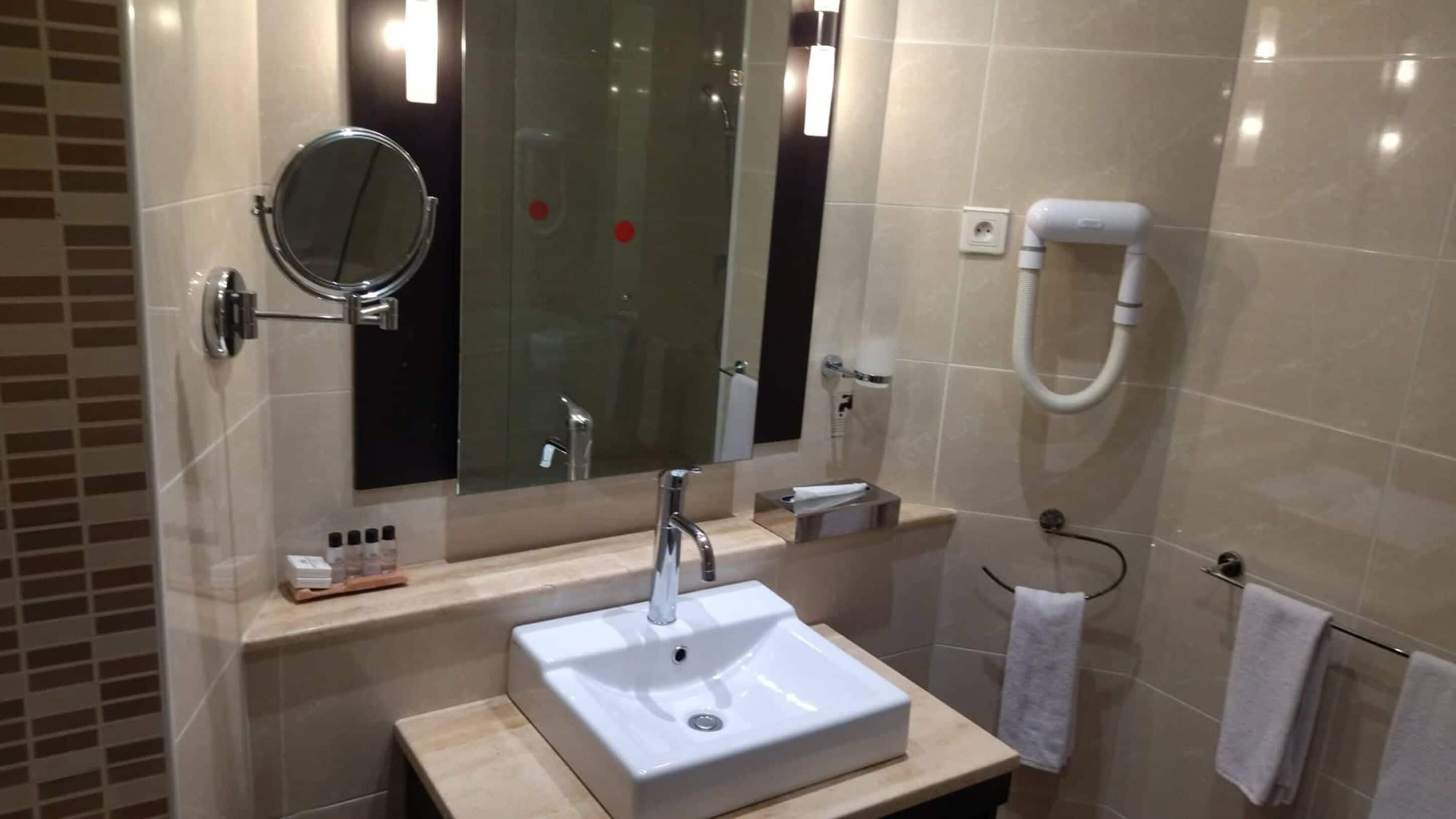 Un baño moderno con un espejo grande, un lavamanos y un perchero para toallas.