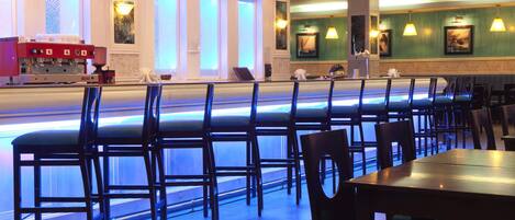 A restaurant with a long counter, multiple chairs, and tables.