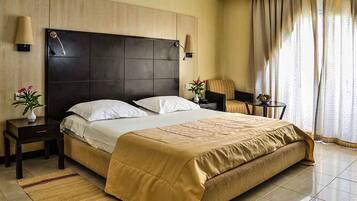 Une chambre d’hôtel avec un grand lit, deux tables de chevet, une chaise et une petite table avec une lampe.