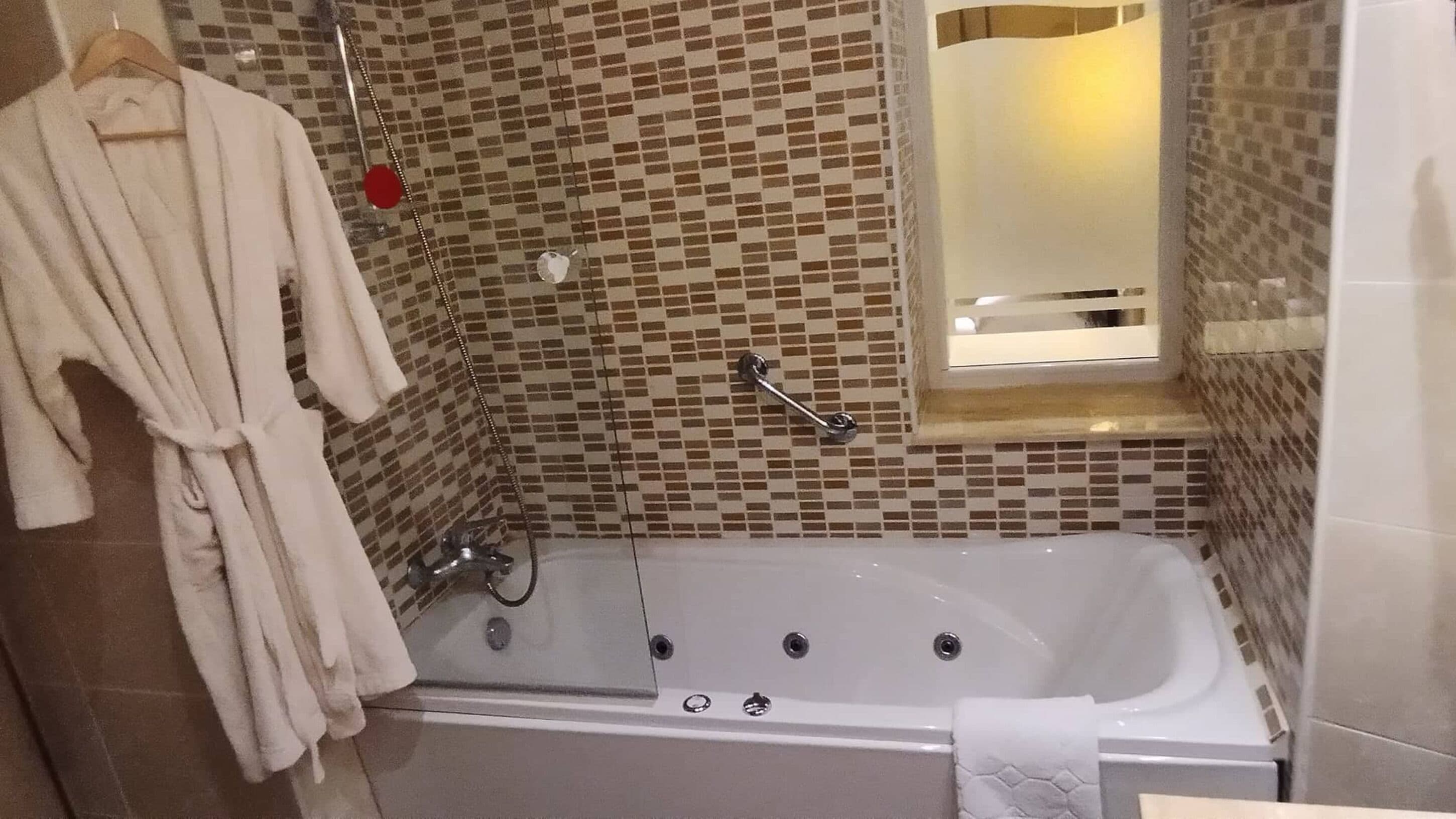 Ein Badezimmer mit Badewanne, Handtuchhalter und Spiegel.