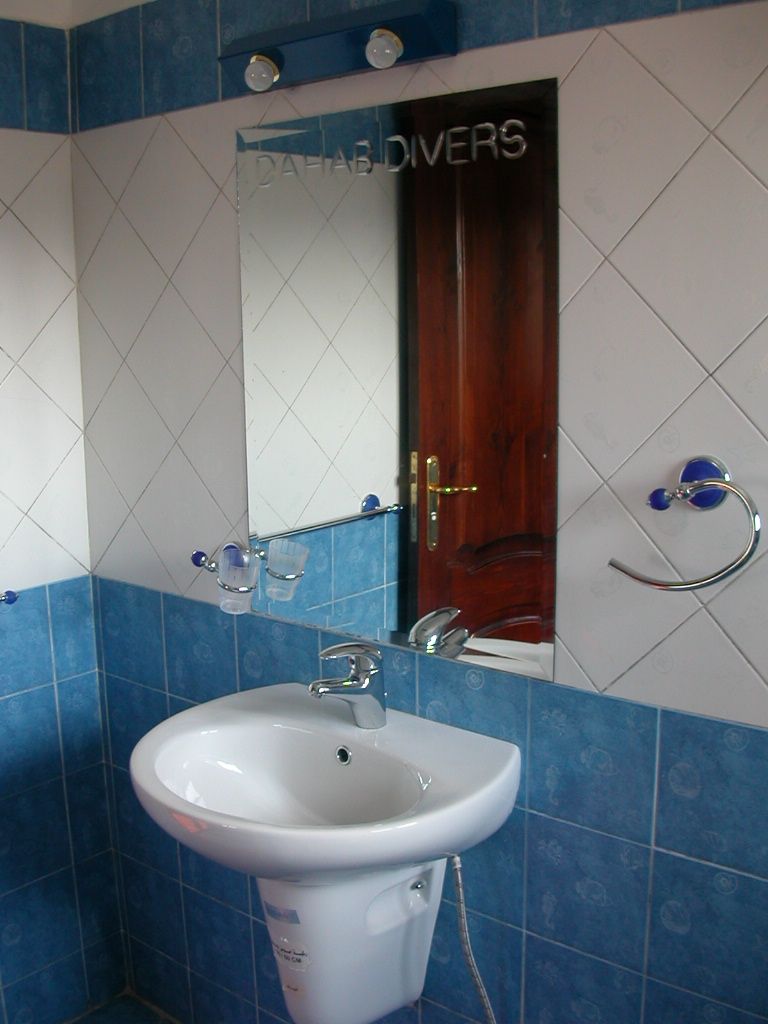 A bathroom with a white sink, a mirror, and a wooden door.