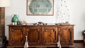 Un mueble de madera con un florero verde, una tetera y un azucarero encima.