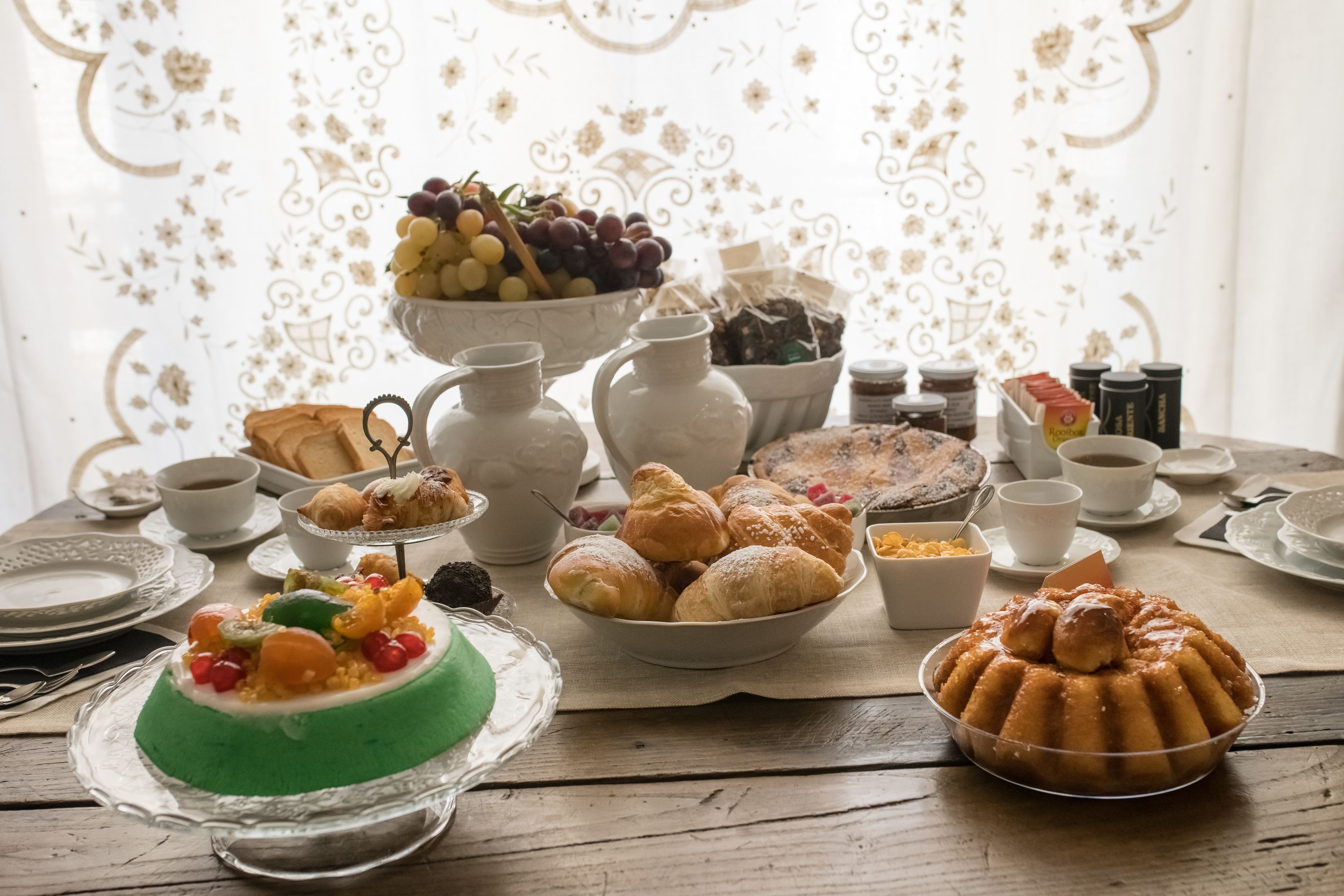 Ein Tisch mit verschiedenen Speisen, darunter Gebäck, ein grünes Dessert und eine Obstschale.