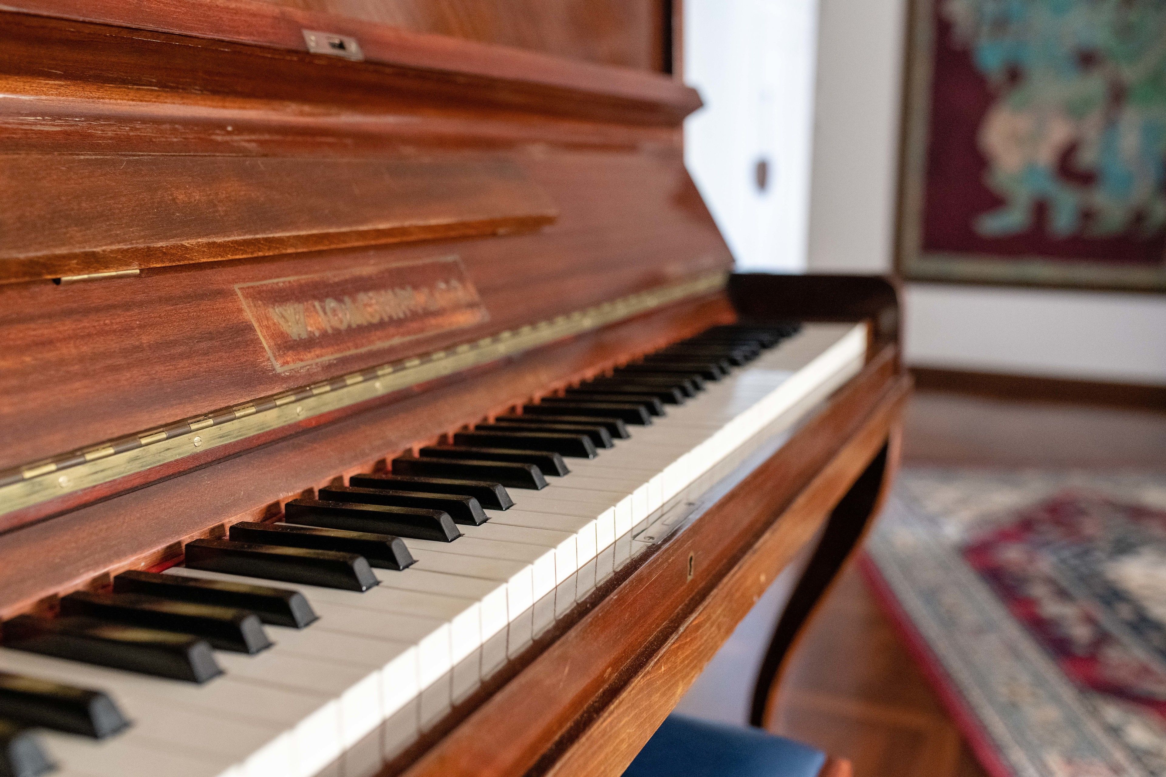 Un piano de cola con un acabado de madera pulido y una marca visible.
