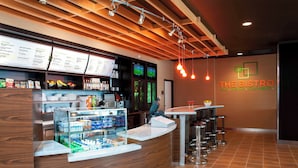 Interior de restaurante con techo de madera, mostrador con vitrina y un panel de menú.
