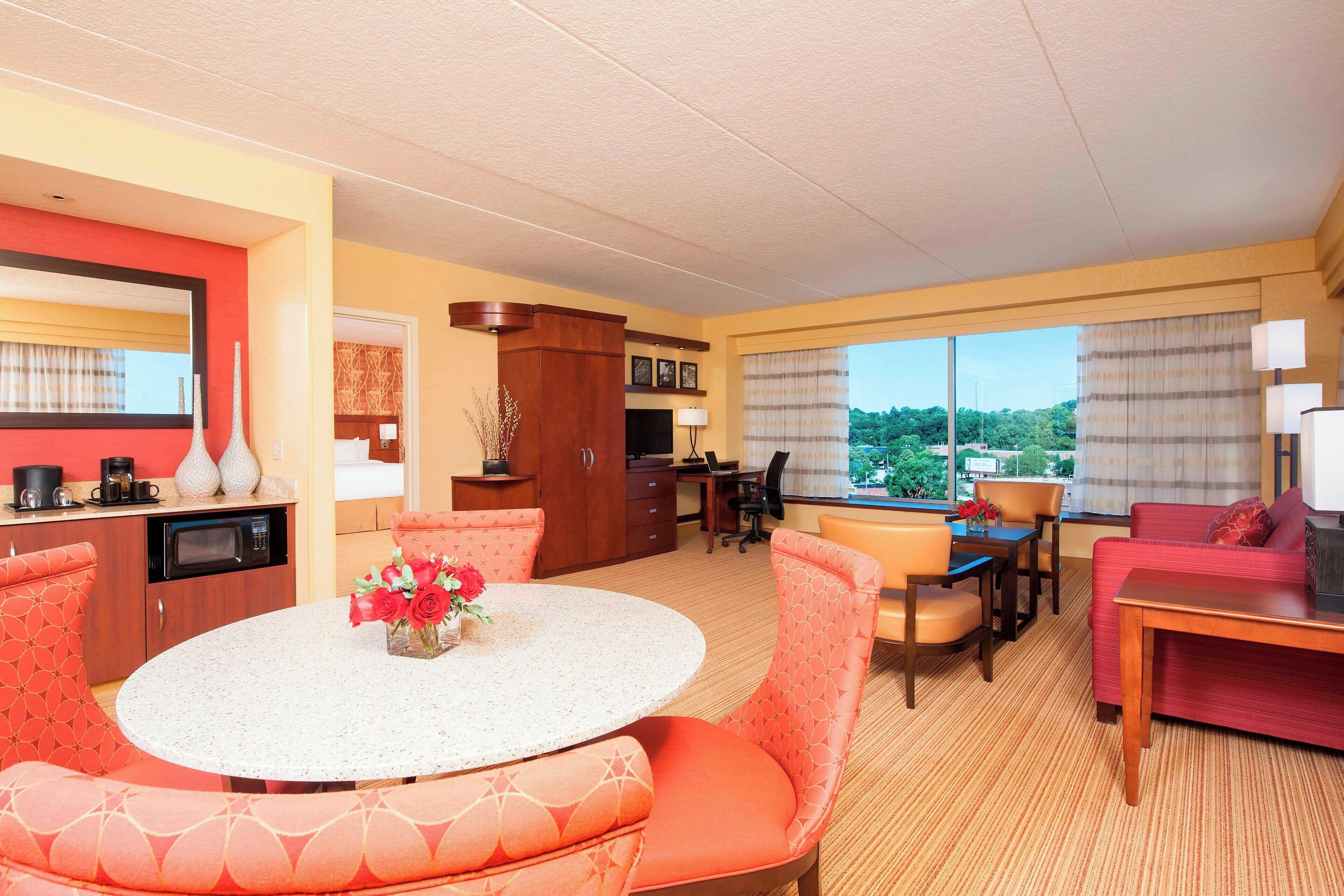 A hotel room with a dining area, a kitchen, and a living area with a view.