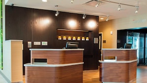 Zona de recepción con dos mostradores de madera, una pantalla digital y una máquina expendedora.