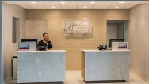 Ein Hotelrezeptionstresen mit Marmordesign, einem digitalen Bildschirm und einem Schild für Holiday Inn Express Suites.