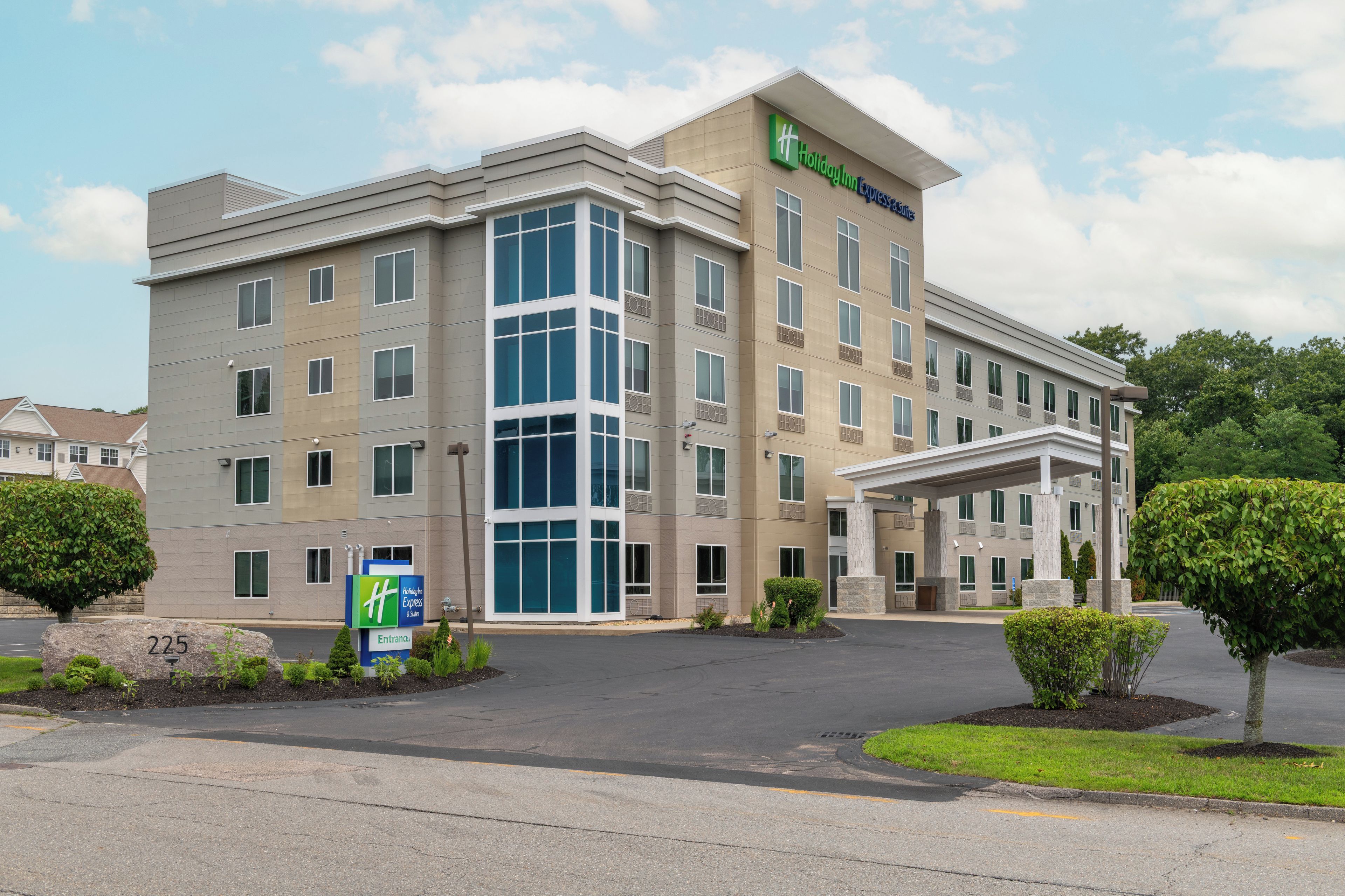 A Holiday Inn Express & Suites hotel with a modern design, featuring a large entrance and a covered outdoor area.