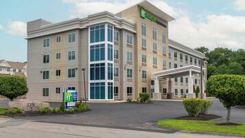A Holiday Inn Express & Suites hotel with a modern design, featuring a large entrance and a covered outdoor area.