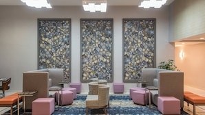 Eine Lobby mit Sitzgelegenheiten, einer gemusterten Wand und einer Deckenleuchte.