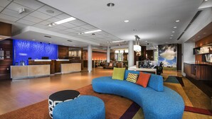 A modern lobby with a reception desk, seating area, and a large window with a view of the sky. - Fairfield Inn & Suites Little Rock Benton (Benton)