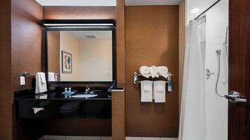 Une salle de bain moderne avec un lavabo noir, un grand miroir et un espace douche.