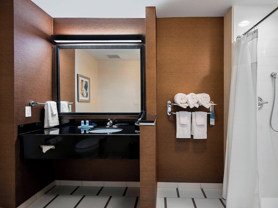 Une salle de bain moderne avec un lavabo noir, un grand miroir et un espace douche.