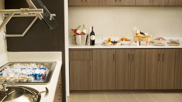 A kitchen with a buffet setup, including a wine bottle, glasses, and various food items. - Residence Inn by Marriott Tyler (Tyler)