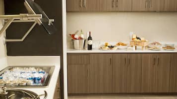 A kitchen with a buffet setup, including a wine bottle, glasses, and various food items.