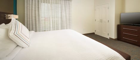 Una habitación de hotel con una cama grande, un televisor en una cómoda y un armario.